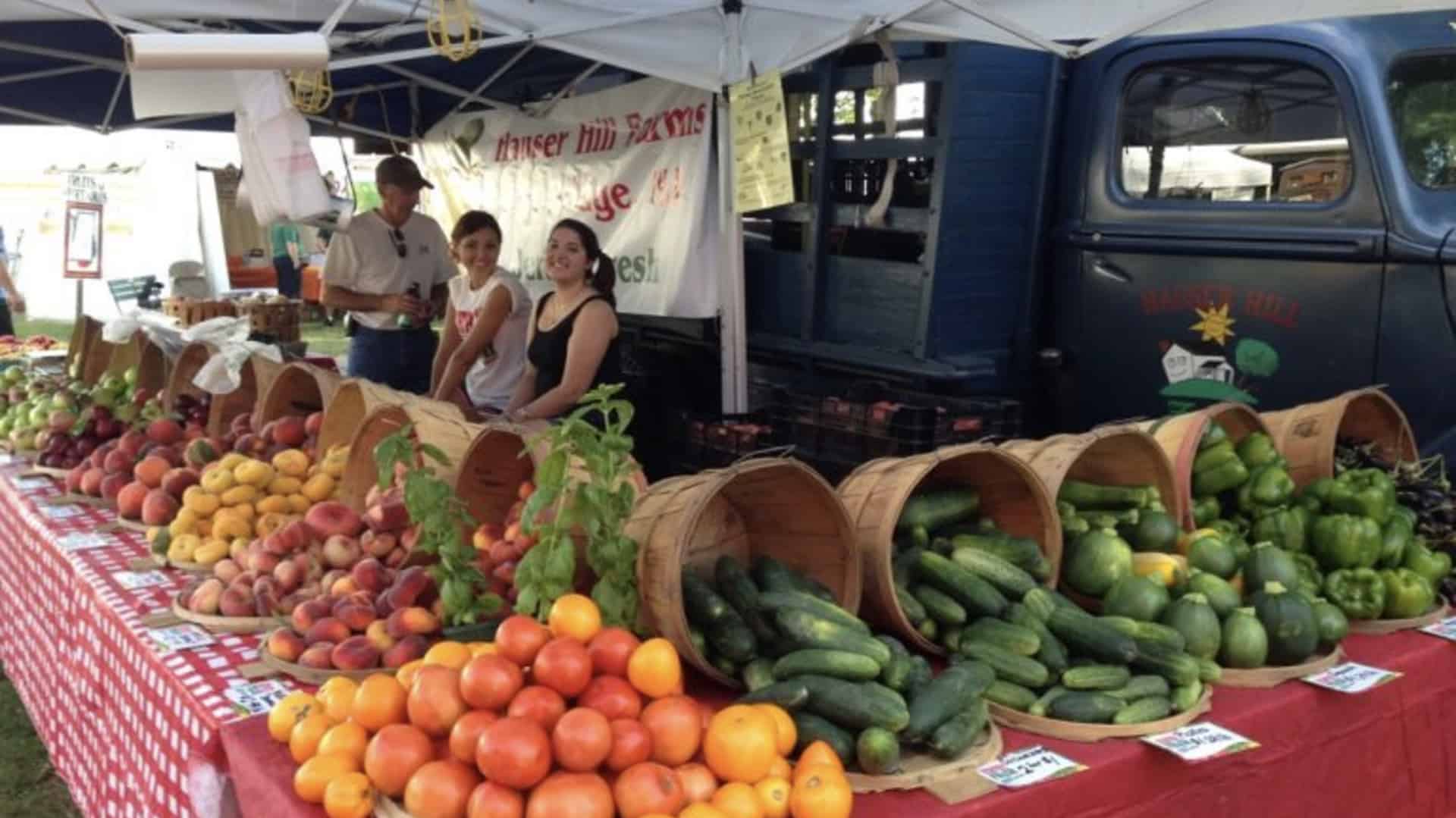 people sell produce at a farmers market
