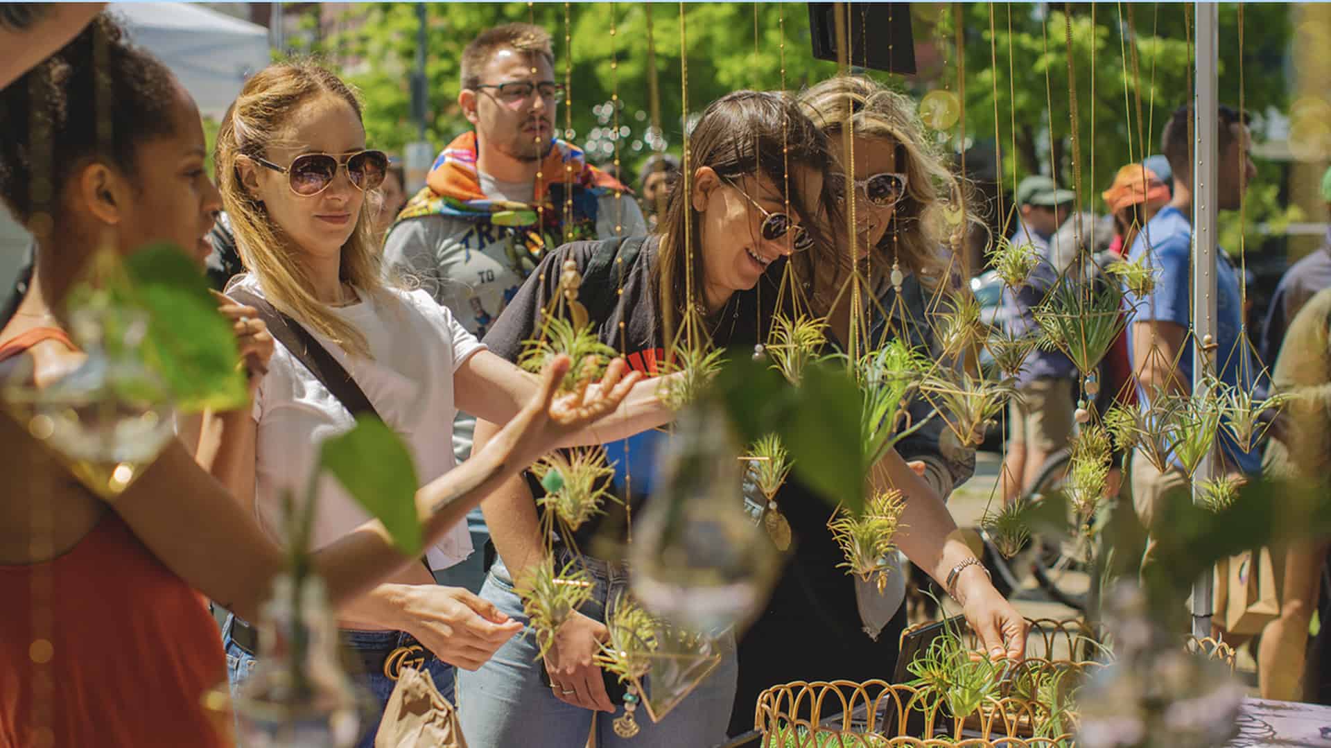 women buy plants at a farmers market