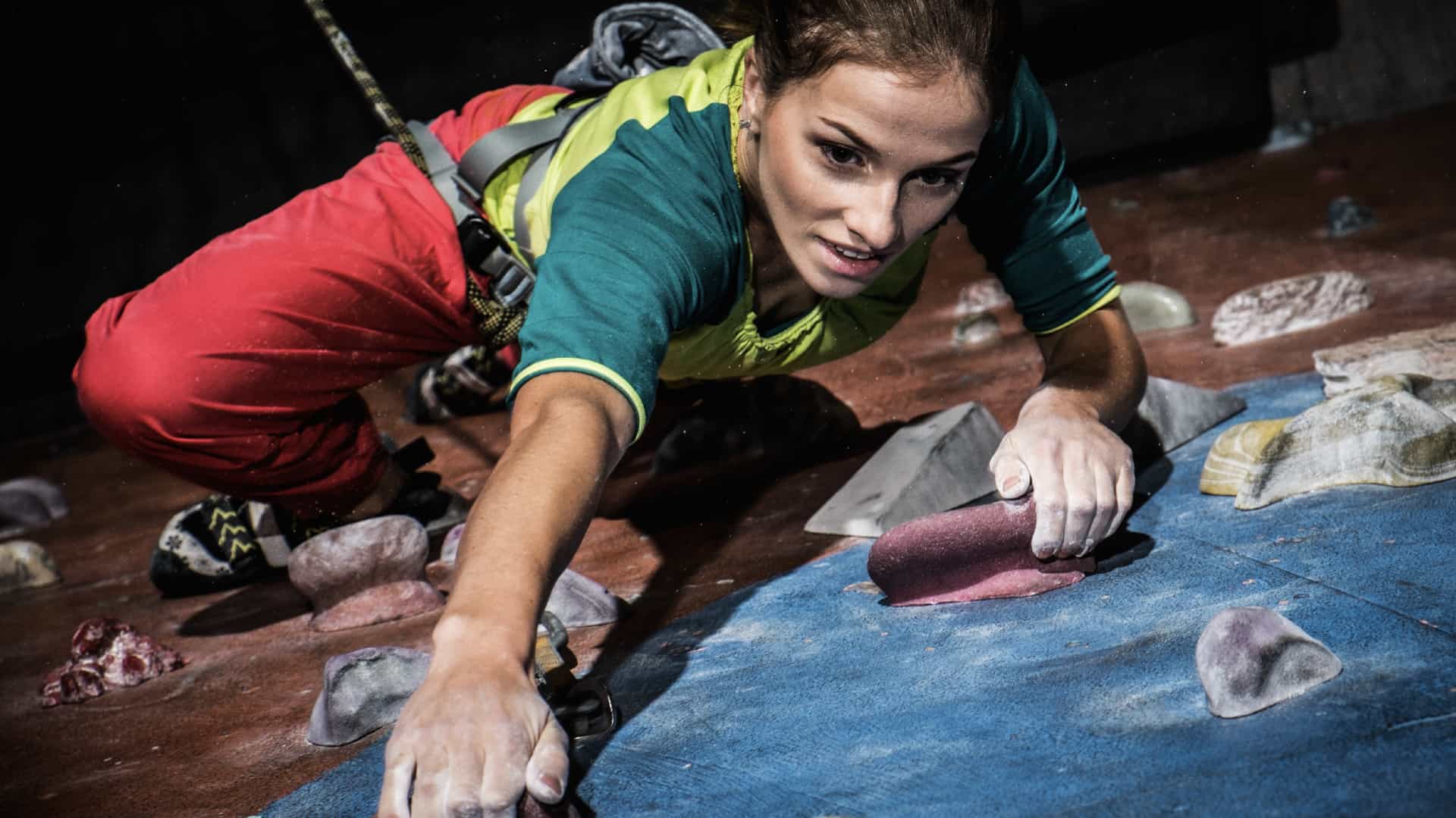 a young woman practicing rock climbing on a rock wall indoors