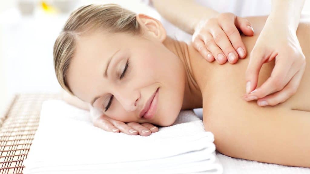 a happy person lays on a table while receiving acupuncture treatment