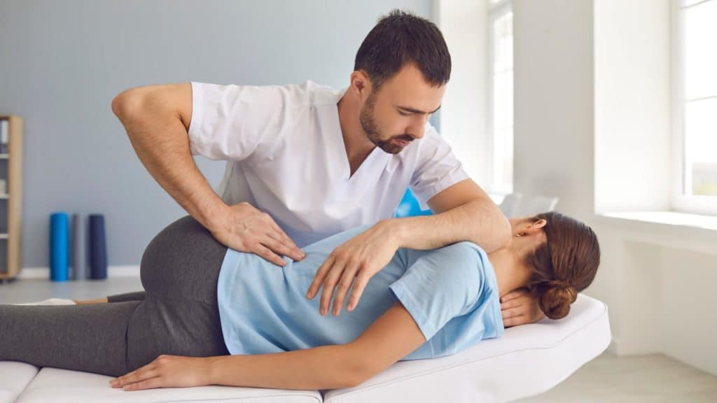 a chiropractor stretches out a patient’s back
