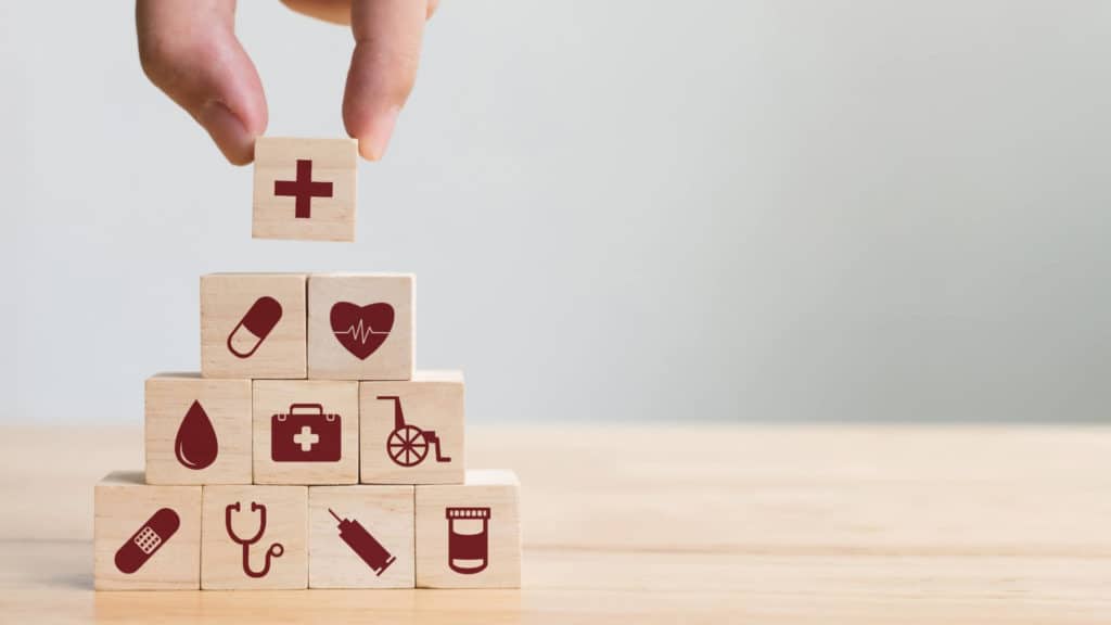 a hand stacks wood blocks with different medical concepts on each block