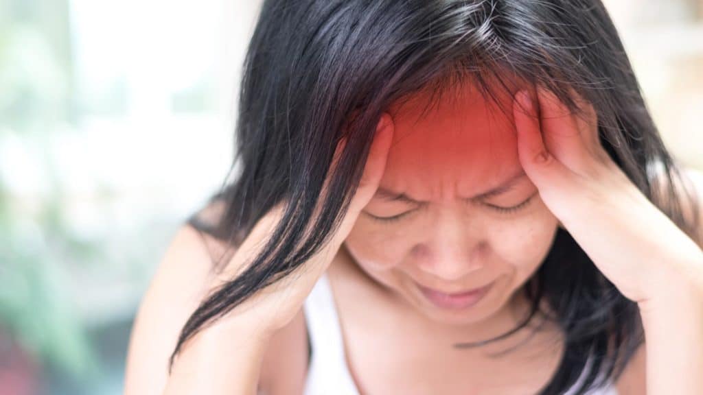 a person with neurological disorders grips their head