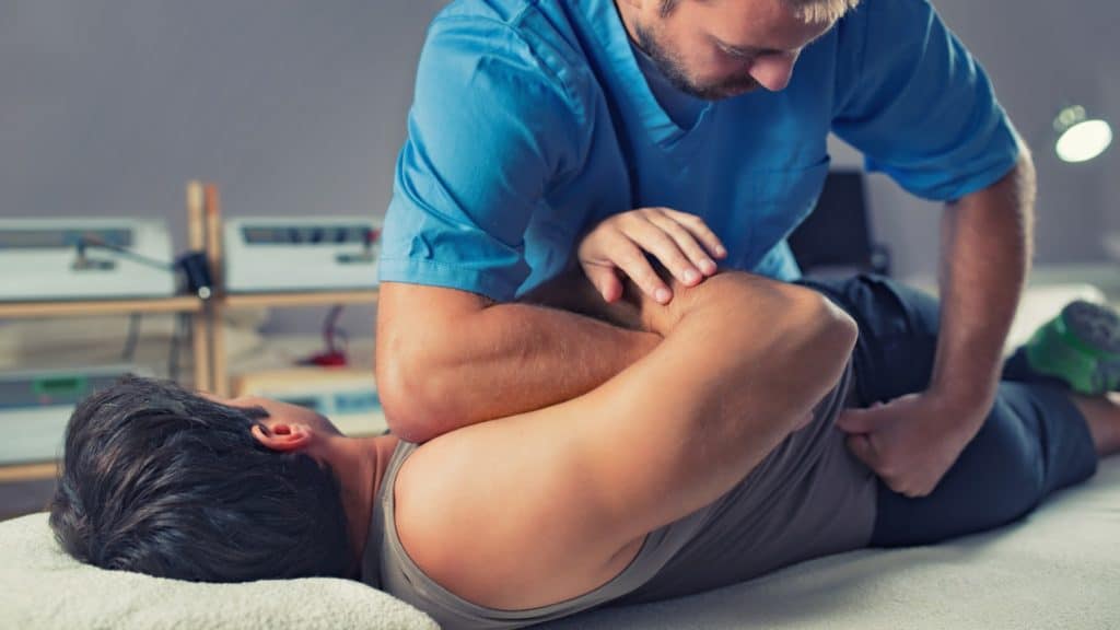 a chiropractor performs a back adjustment on a patient
