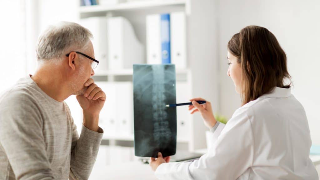 a doctor shows X-ray of a spine to a senior citizen