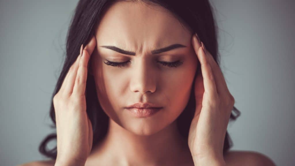 a person with a headache touches their temples