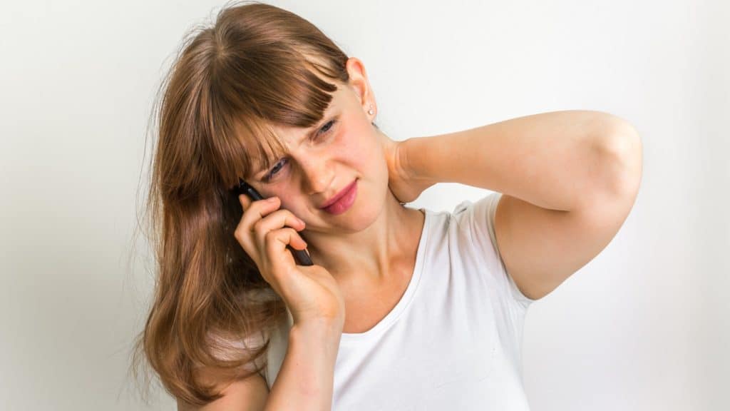 a person with neck pain talks on phone