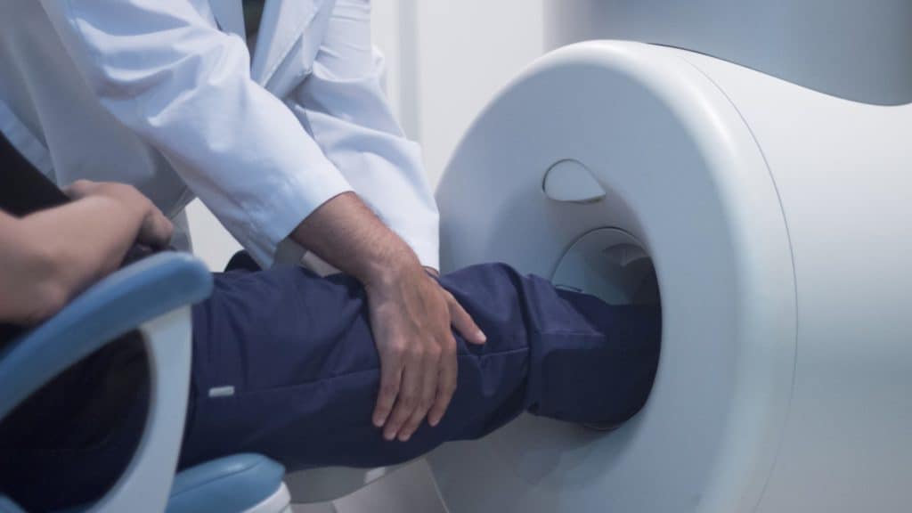 a doctor performs an MRI on a patient's knee