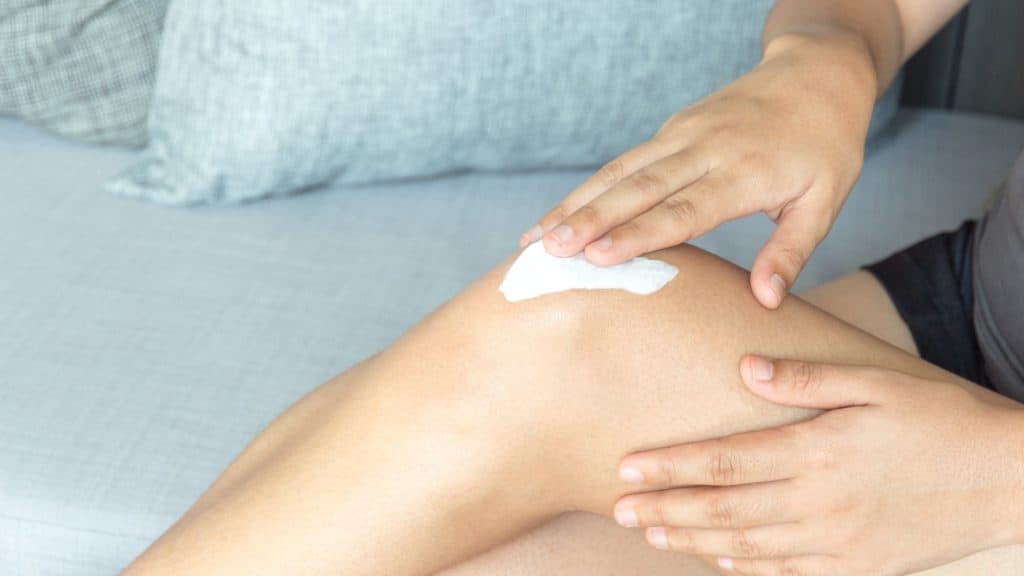 a person applies topical medication on their knee