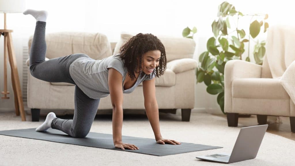 a person exercises at home while watching a video tutorial