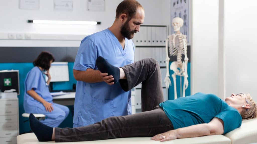a practitioner helps a patient with knee pain
