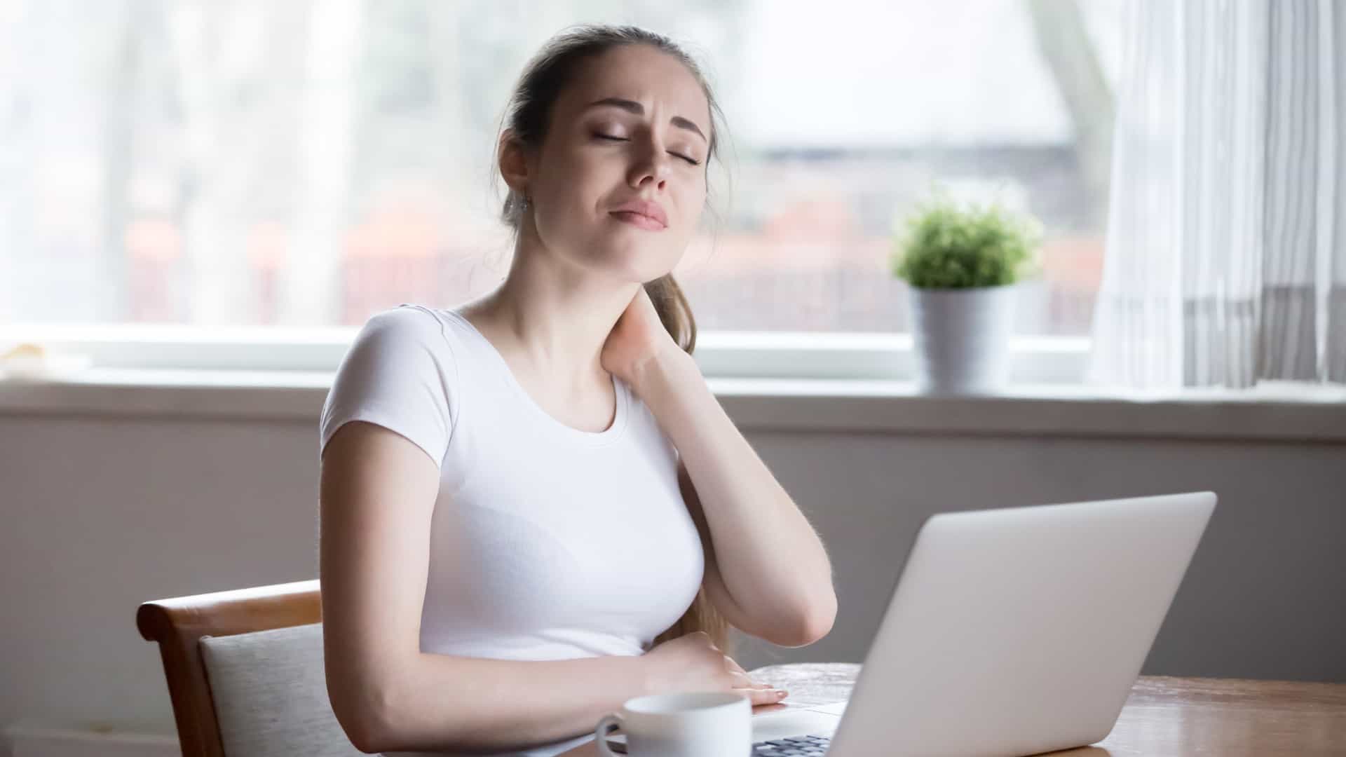 Woman holding neck in discomfort while at desk | How To Identify Tech Neck | Northeast Spine and Sports Medicine