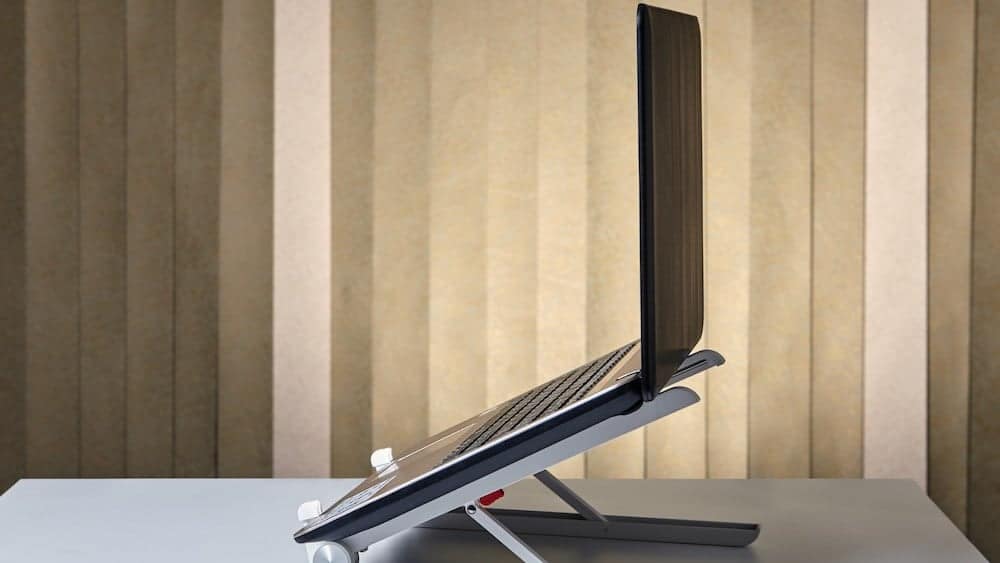 Laptop resting on an angled stand | Adjust the Height of Your Desk | Northeast Spine and Sports Medicine