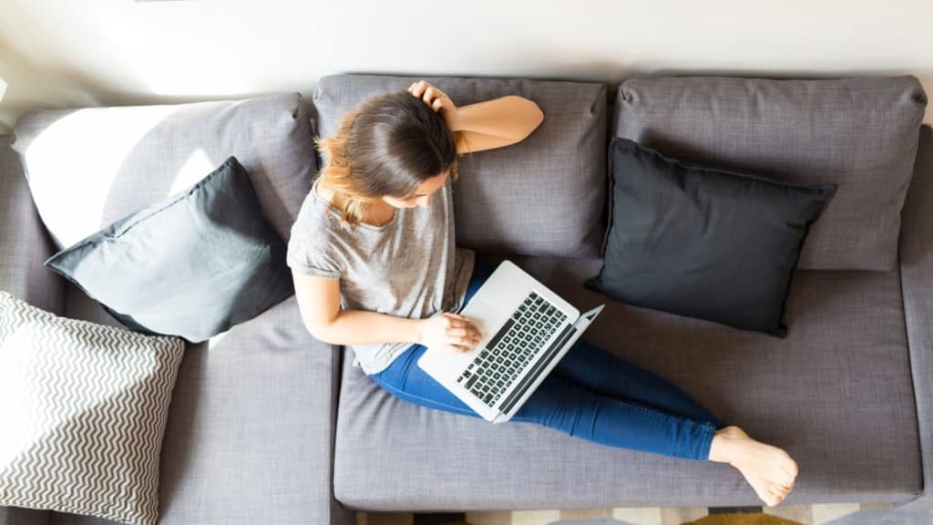 Woman sitting on couch with laptop | How Common Is Tech Neck? | Northeast Spine and Sports Medicine