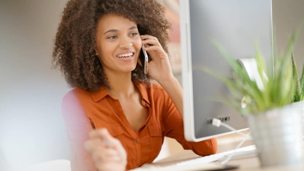 Woman on the phone at her desk | Seek Expert Care For Tech Neck | Northeast Spine and Sports Medicine