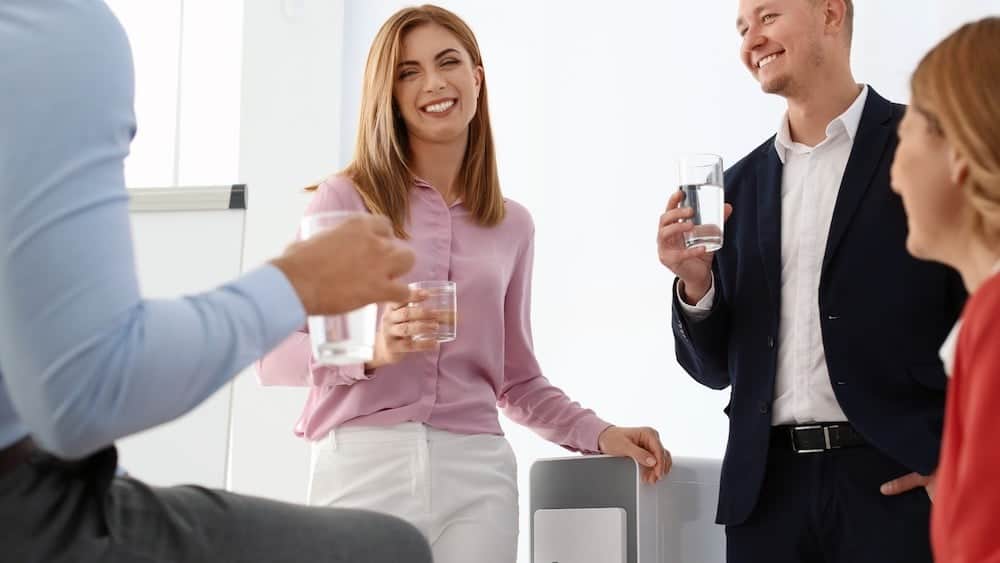 Group of people standing at water cooler | Take Plenty of Breaks | Northeast Spine and Sports Medicine