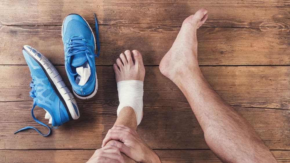 Running shoes next to an athlete's taped foot | Northeast Spine and Sports Medicine