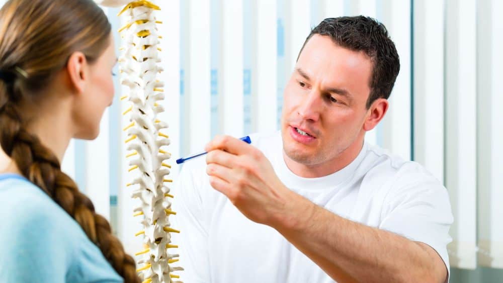 Chiropractor pointing at model of a spine with pen | Northeast Spine and Sports Medicine