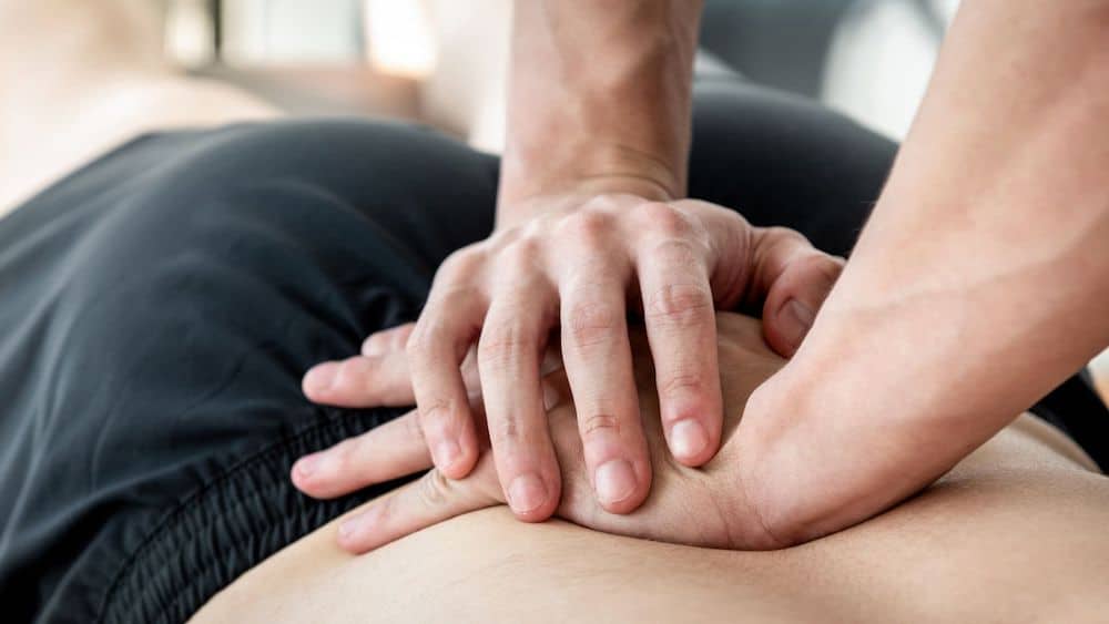 Chiropractor pressing down on patient's lower back | Northeast Spine and Sports Medicine