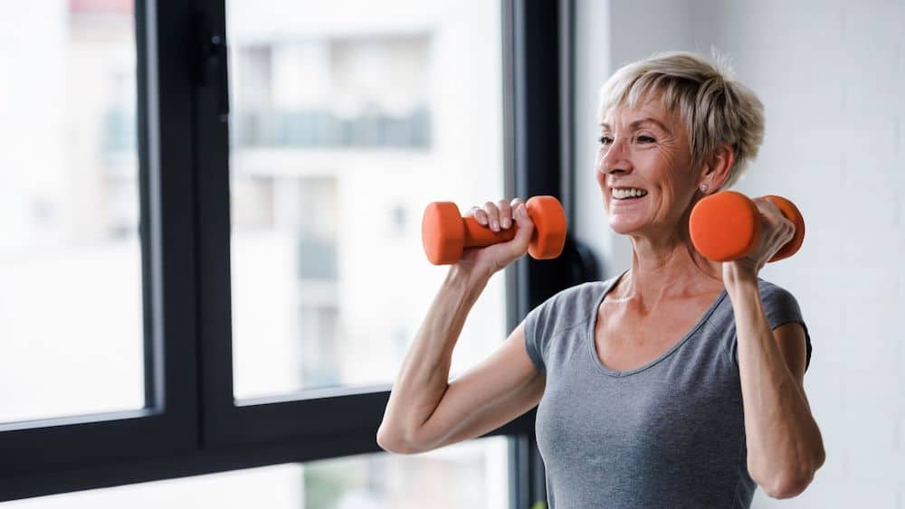 Blonde woman lifting orange weights | Northeast Spine and Sports Medicine