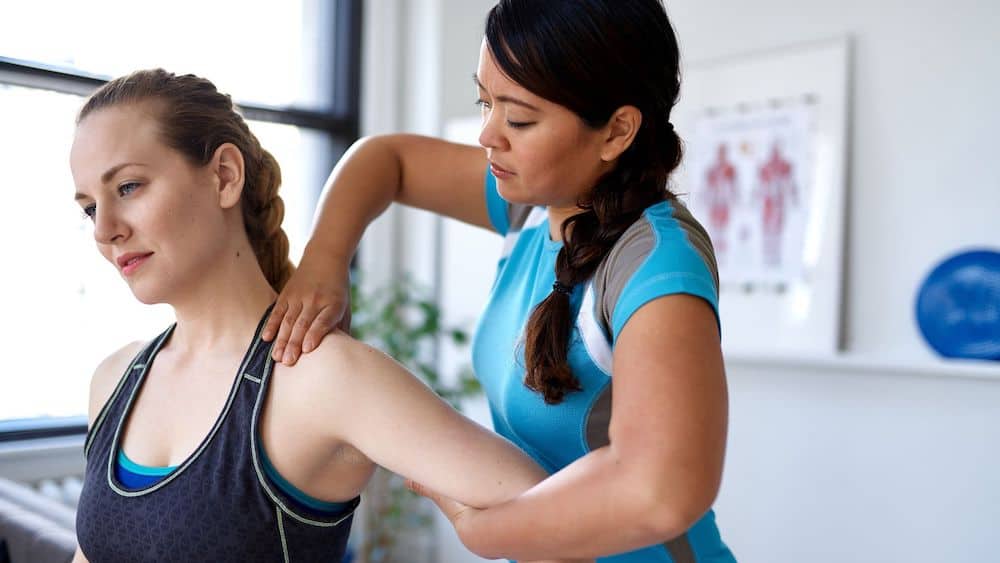 Chiropractor bends a woman's arm backwards to stretch | Northeast Spine and Sports Medicine