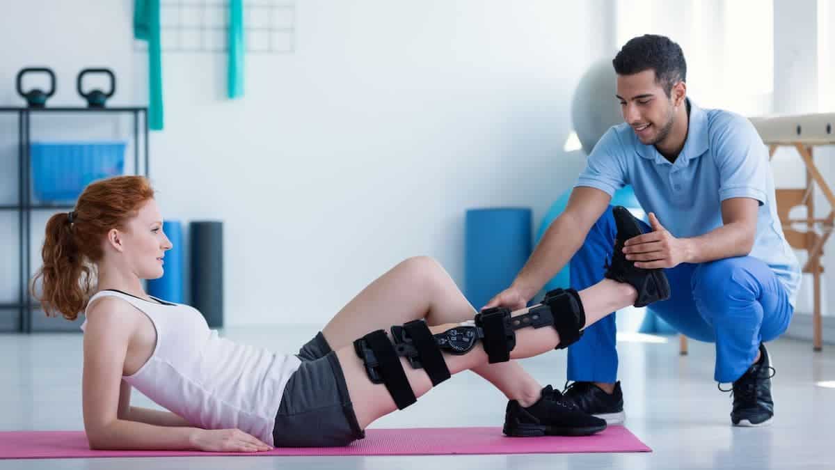 Woman laying with leg extended as physical therapist conducts exam | NorthEast Spine and Sports Medicine