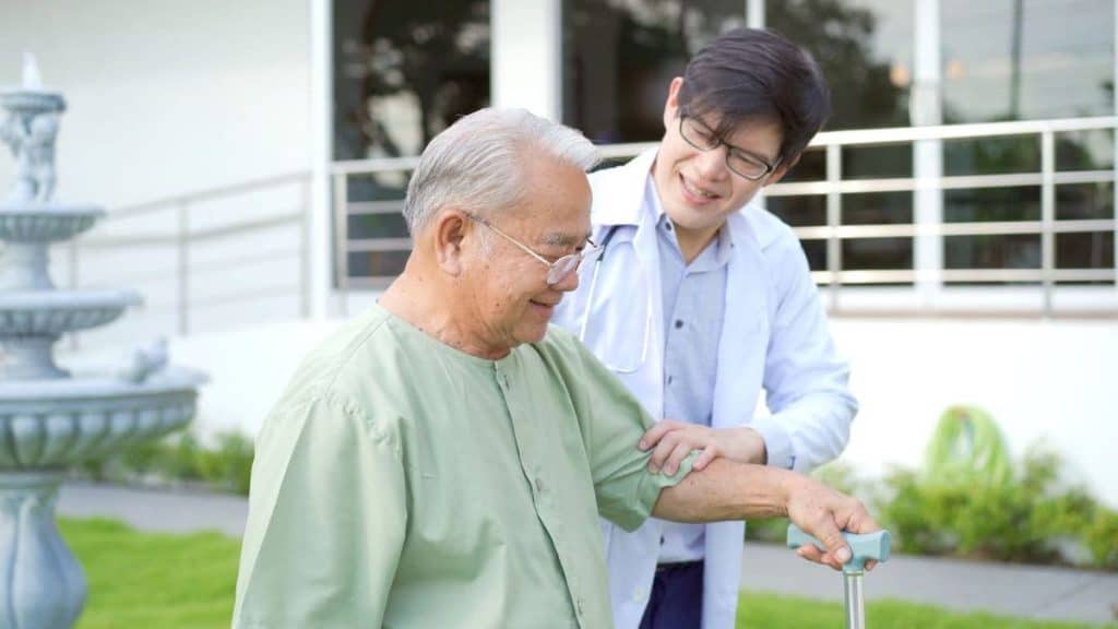 Physical therapist walking with an elderly man with a cane outdoors | NorthEast Spine and Sports Medicine