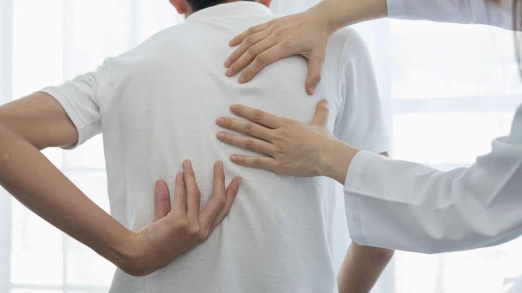 Boy showing doctor place of pain on his back | Back Pain Treatment at Northeast Spine and Sports Medicine