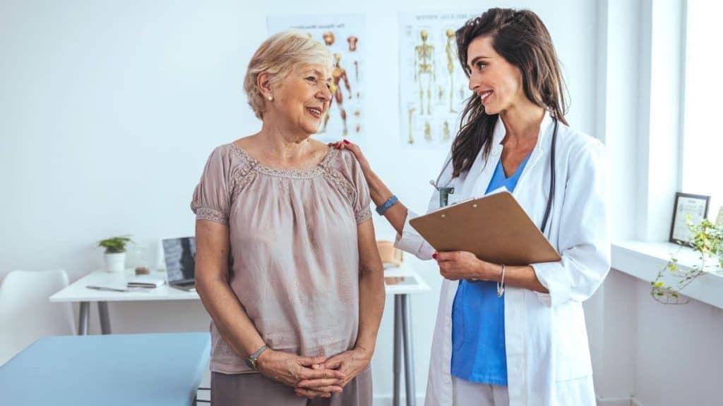 Female doctor holds patients shoulder while smiling | Acupuncture for Back Pain at Northeast Spine and Sports Medicine