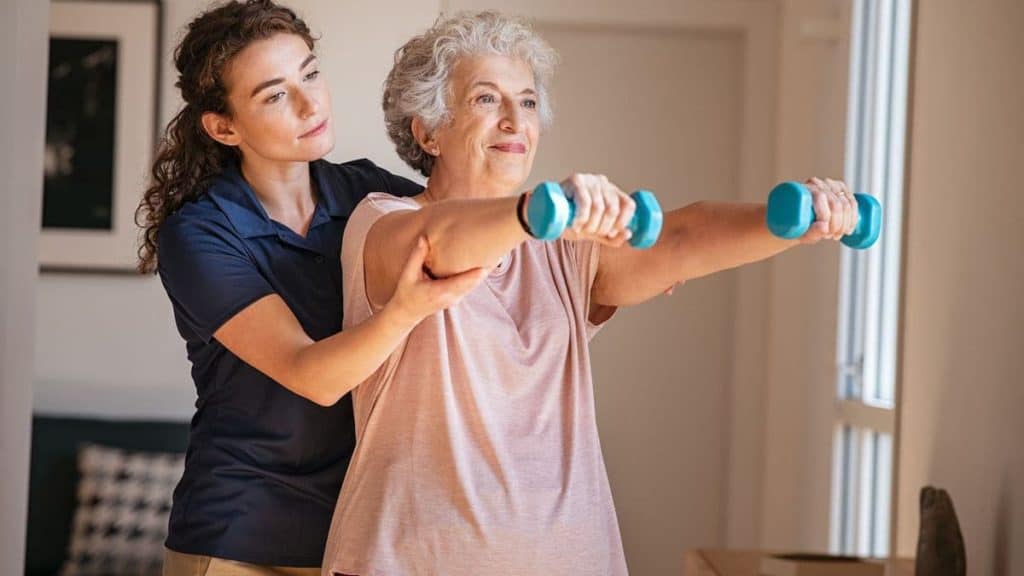 Physical therapist helping elderly woman lift weights | Back Pain Treatment at Northeast Spine and Sports Medicine
