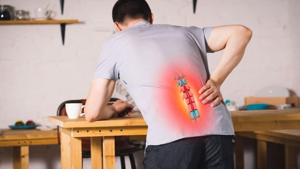 Spine diagram on man's back as he is hunched over in pain | Acupuncture for Back Pain at Northeast Spine and Sports Medicine