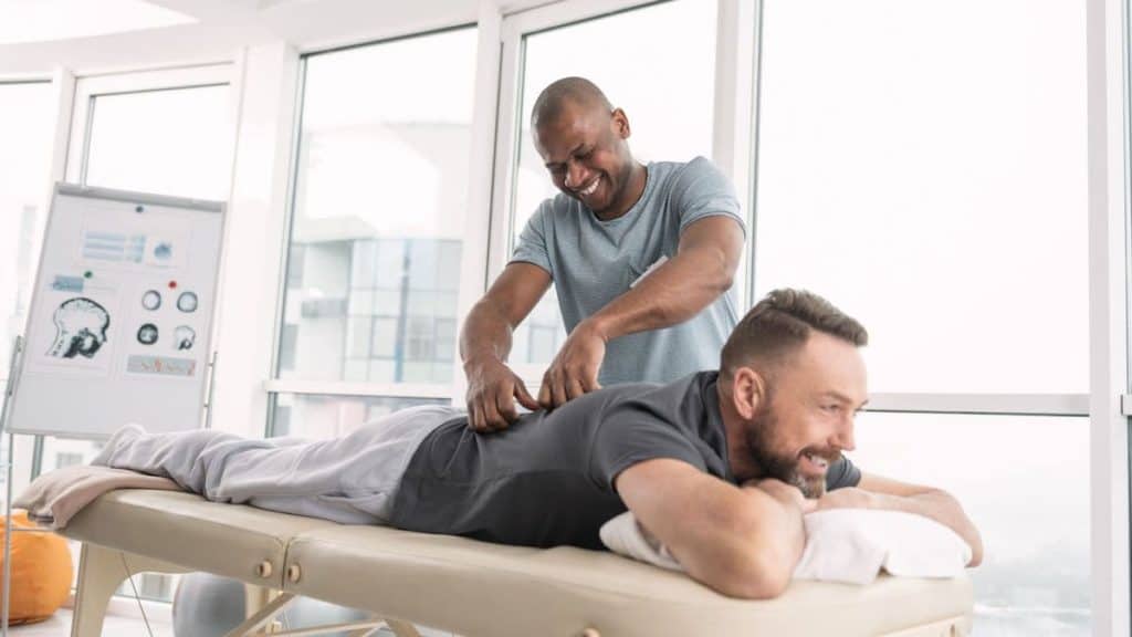 Acupuncturist examines man's back as he lays on table | Acupuncture for Back Pain at Northeast Spine and Sports Medicine