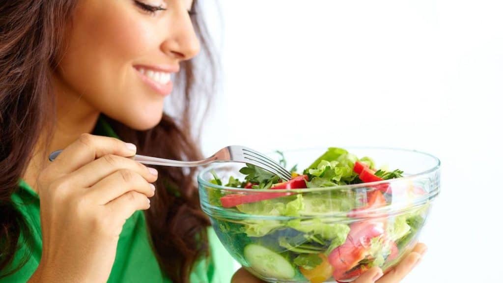 Woman smiling while holding salad | Back Pain Treatment at Northeast Spine and Sports Medicine
