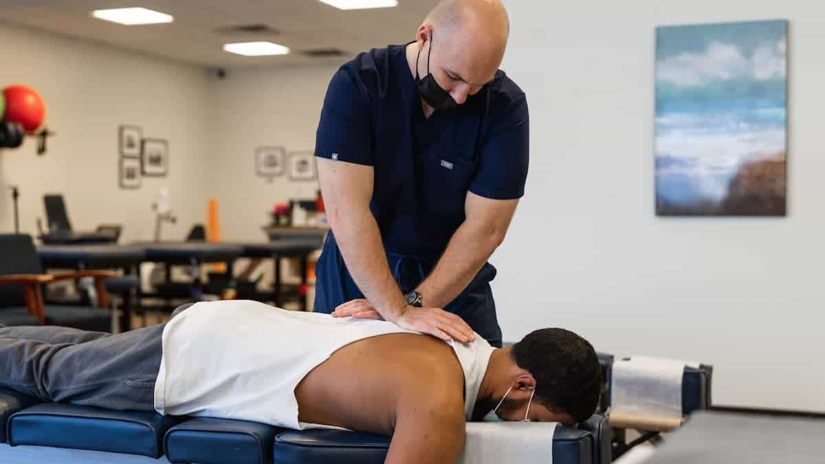Chiropractor pushes down on stressed patient's back while they lay on table | Northeast Spine and Sports Medicine