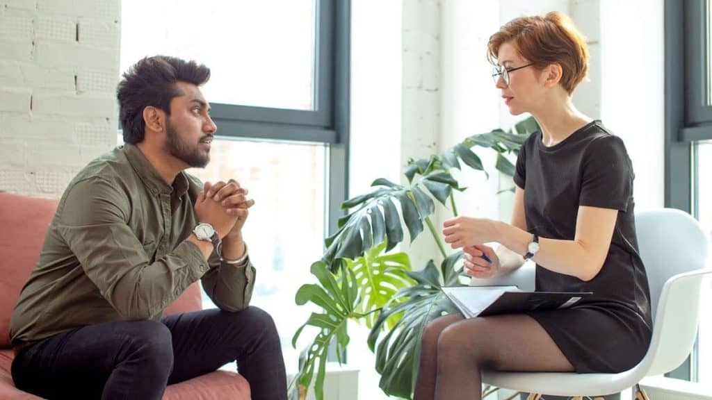 Stressed man talks to behavioral therapist in her office | Northeast Spine and Sports Medicine