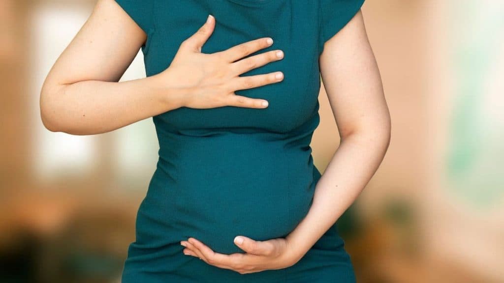 Pregnant woman holding her chest from nausea | Physical therapy at NorthEast Spine and Sports Medicine