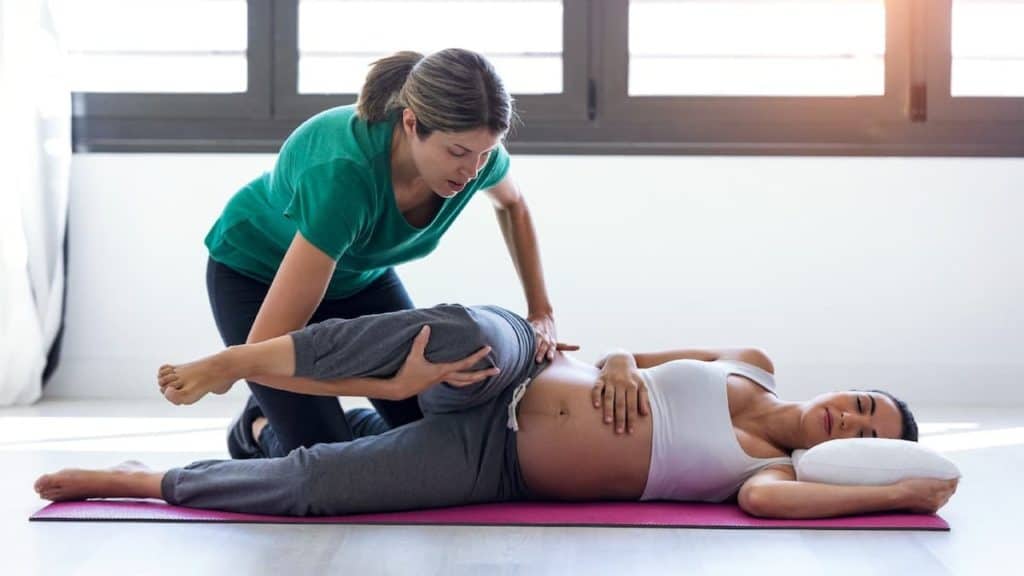 Physical therapist helping to stretch a pregnant patient's leg | NorthEast Spine and Sports Medicine