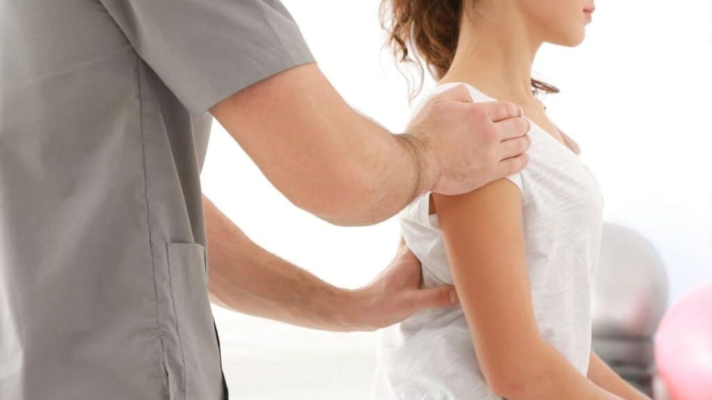 Chiropractor Puts Hands on Woman's Shoulders to Adjust Spine | Chiropractor Statistics